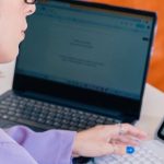 Professional Setup - A woman in a purple shirt is using a laptop