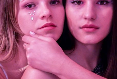 User-friendly - Two young women posing for a photo in front of a pink and silver curtain