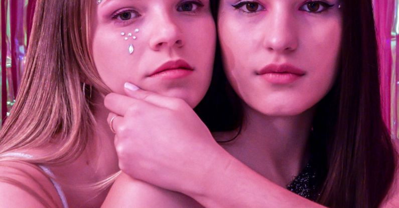 User-friendly - Two young women posing for a photo in front of a pink and silver curtain