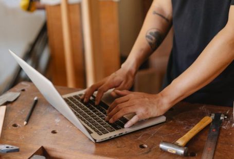 DIY Computer - From above of crop anonymous male joiner with tattoo surfing internet on netbook in workshop