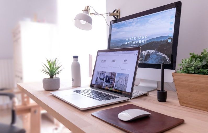 Network Setup - MacBook Pro on table beside white iMac and Magic Mouse